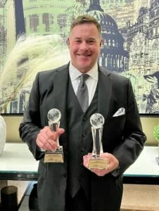 John Hill posed with two awards