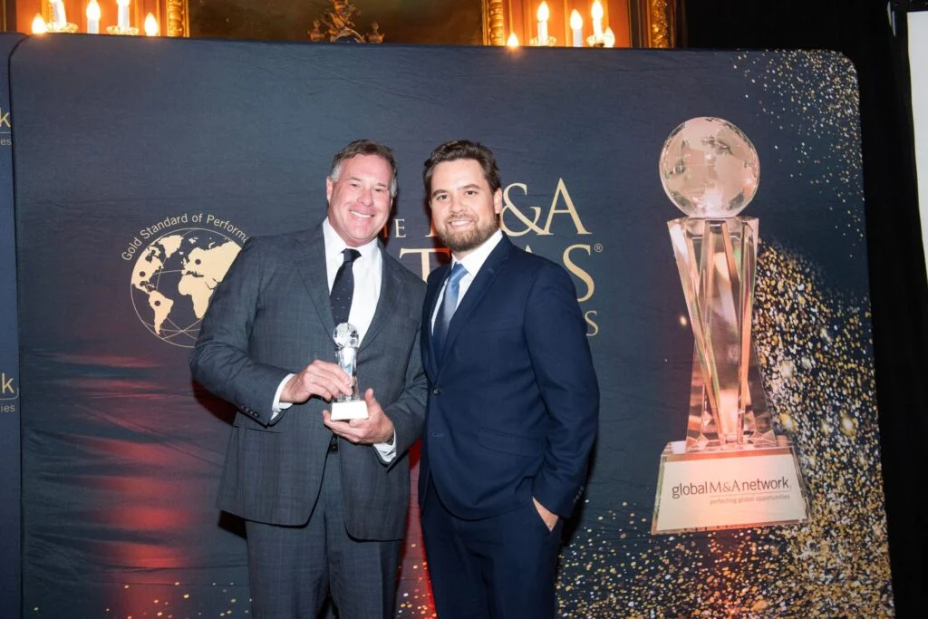 Two men posing with an award trophy.
