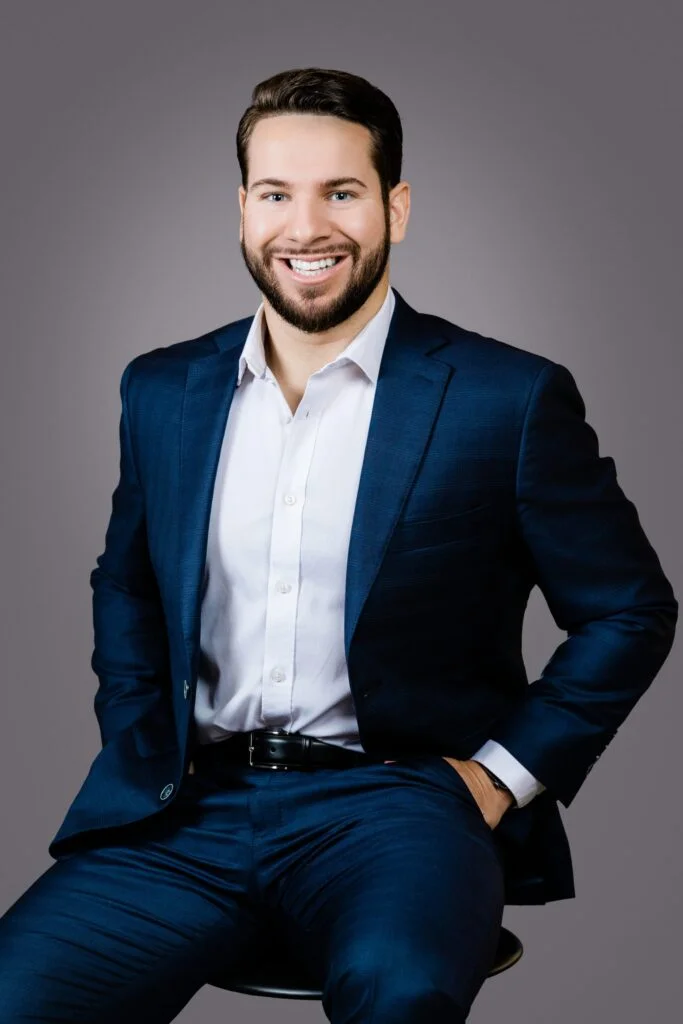 Professional headshot of Luke Horanski, Vice President at Hyde Park Capital, specializing in industrial, business services, and consumer sectors, wearing a navy blue suit and seated against a neutral background.
